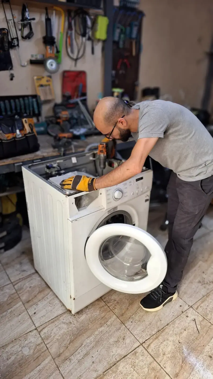 المهندس أيمن أثناء صيانة غسالة أوتوماتيك في ورشة كيت بوكس